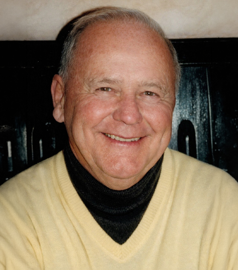 Photo of Jack O’Neill smiling, wearing a light yellow sweater over a dark turtleneck.